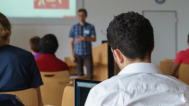 Ein Student hört sich einen Vortrag eines Dozenten an.
