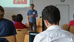Ein Student hört sich einen Vortrag eines Dozenten an.