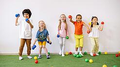 Kleinkinder werfen mit bunten Bällen.
