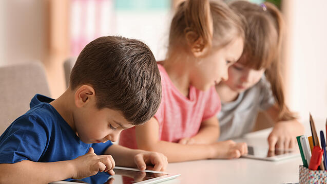Kleine Kinder spielen am Tablet.