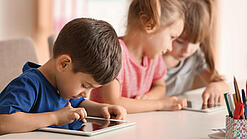 Kleine Kinder spielen am Tablet.