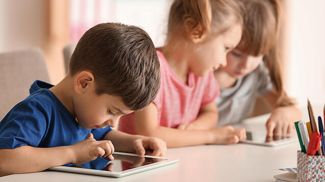 Kleine Kinder spielen am Tablet.