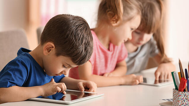 Kleine Kinder spielen am Tablet.