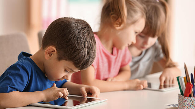 Kleine Kinder spielen am Tablet.