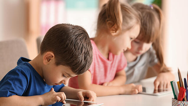 Kleine Kinder spielen am Tablet.
