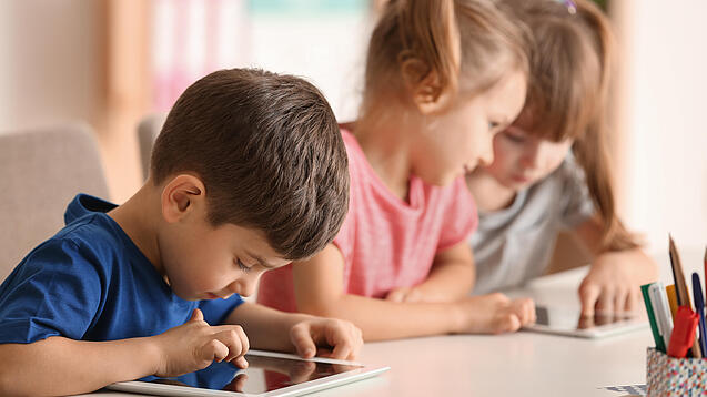 Kleine Kinder spielen am Tablet.