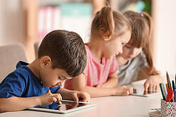 Kleine Kinder spielen am Tablet.