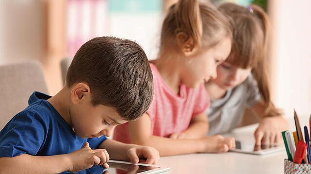 Kleine Kinder spielen am Tablet.