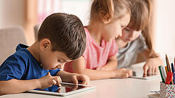 Kleine Kinder spielen am Tablet.