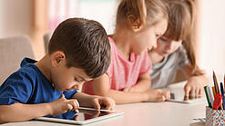 Kleine Kinder spielen am Tablet.