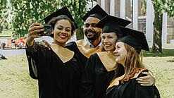 Eine Gruppe Graduierter schießt ein Selfie mit einem Smartphone.
