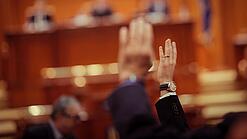 Mehrere Menschen heben in einer Abstimmung ihre Hand.