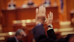 Mehrere Menschen heben in einer Abstimmung ihre Hand.