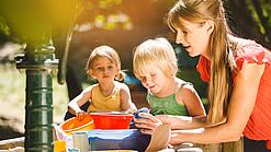 Eine pädagogische Fachkraft spielt mit Kindern im Garten.
