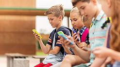 Kinder spielen auf dem Pausenhof am Handy.