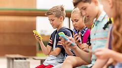 Kinder spielen auf dem Pausenhof am Handy.