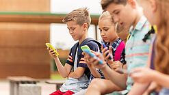 Kinder spielen auf dem Pausenhof am Handy.