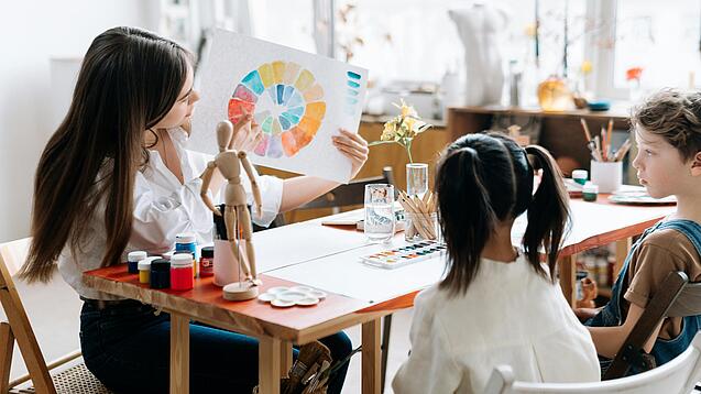 Junge Lehrerin zeigt zwei Kindern einen Farbkreis