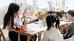 Junge Lehrerin zeigt zwei Kindern einen Farbkreis