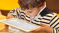 Ein kleines Kind schaut auf ein Tablet.