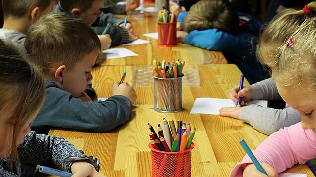 Kinder malen an einem Tisch.