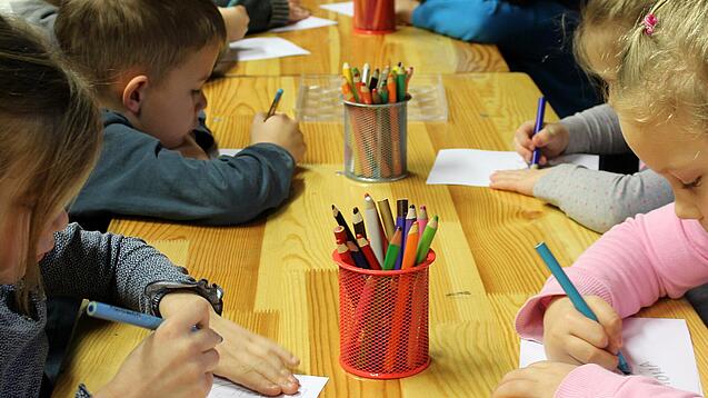Kinder malen an einem Tisch.