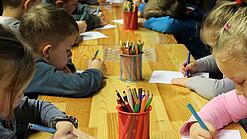 Kinder malen an einem Tisch.