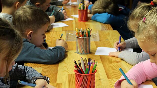 Kinder malen an einem Tisch.