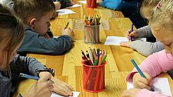 Kinder malen an einem Tisch.