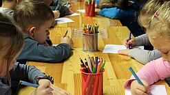 Kinder malen an einem Tisch.