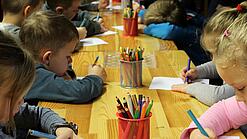 Kinder malen an einem Tisch.