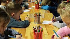 Kinder malen an einem Tisch.
