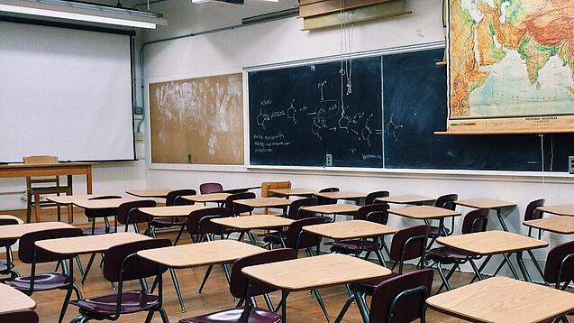 Ein leeres Klassenzimmer mit Stühlen und Pulten.