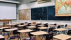 Ein leeres Klassenzimmer mit Stühlen und Pulten.