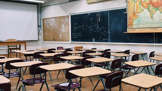 Ein leeres Klassenzimmer mit Stühlen und Pulten.