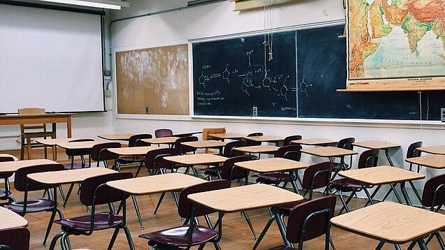 Ein leeres Klassenzimmer mit Stühlen und Pulten.