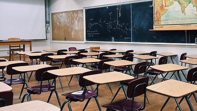 Ein leeres Klassenzimmer mit Stühlen und Pulten.