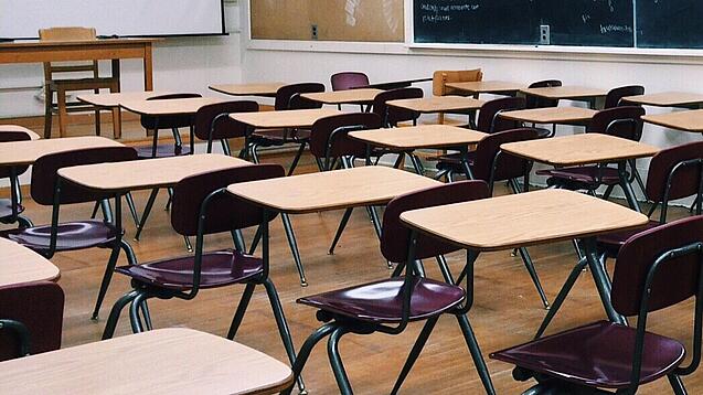Ein leeres Klassenzimmer mit Stühlen und Pulten.