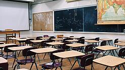 Ein leeres Klassenzimmer mit Stühlen und Pulten.