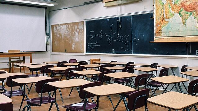 Ein leeres Klassenzimmer mit Stühlen und Pulten.