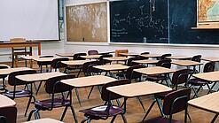 Ein leeres Klassenzimmer mit Stühlen und Pulten.
