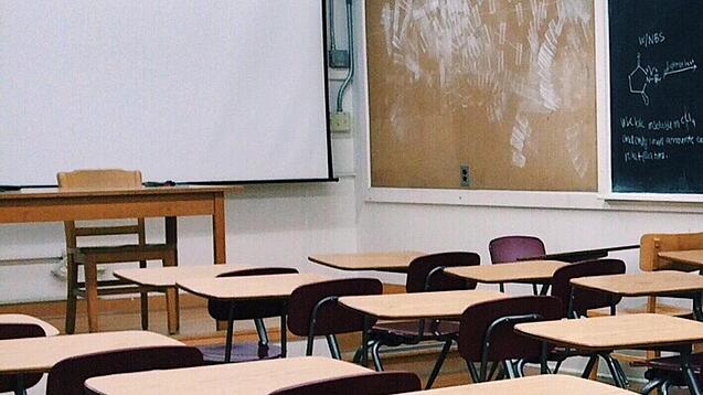 Ein leeres Klassenzimmer mit Stühlen und Pulten.