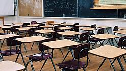 Ein leeres Klassenzimmer mit Stühlen und Pulten.