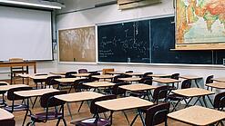 Ein leeres Klassenzimmer mit Stühlen und Pulten.