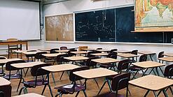 Ein leeres Klassenzimmer mit Stühlen und Pulten.