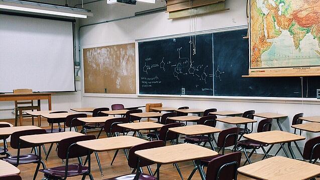 Ein leeres Klassenzimmer mit Stühlen und Pulten.