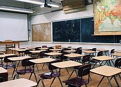 Ein leeres Klassenzimmer mit Stühlen und Pulten.