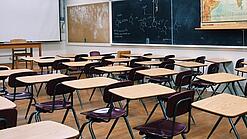 Ein leeres Klassenzimmer mit Stühlen und Pulten.