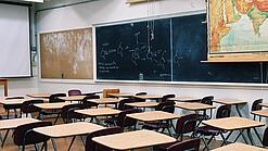Ein leeres Klassenzimmer mit Stühlen und Pulten.