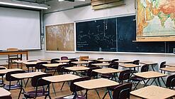 Ein leeres Klassenzimmer mit Stühlen und Pulten.
